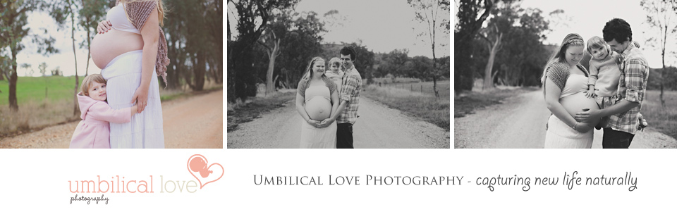 pregnant mum with her partner and toddler holding her pregnant belly looking at camera