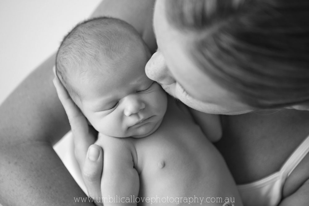new mum kissing her newborn in her arms
