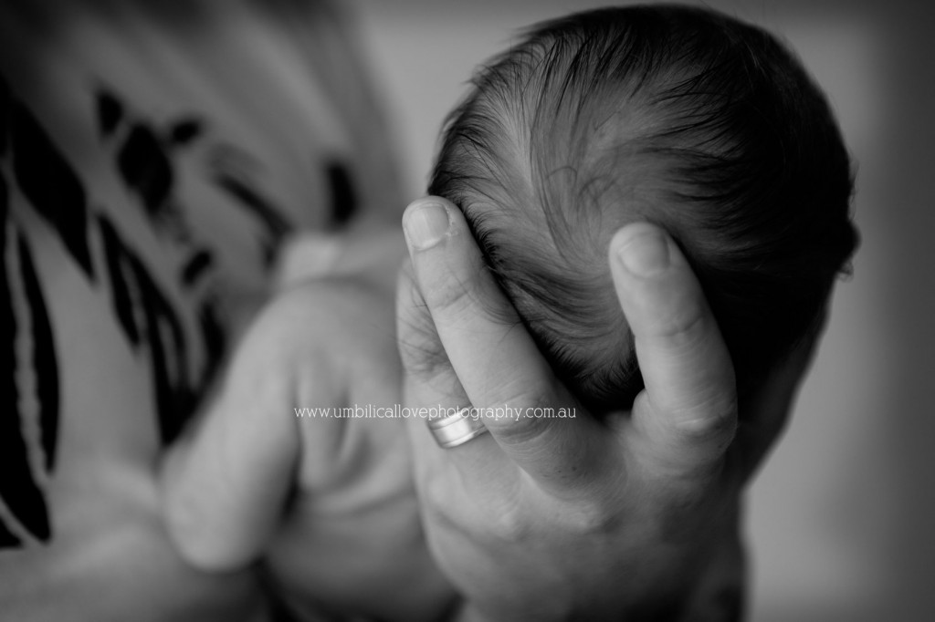 new-dad-with-his-new-baby-documentary-newborn-photographer dad holding his newborn head in his hands with wedding ring on