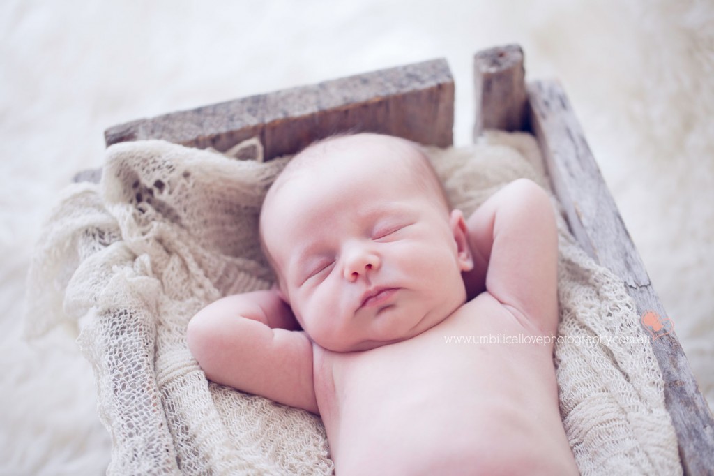 baby in box with arms behind head sleeping