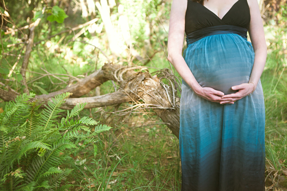 lady holding her pregnant belly in the forrest