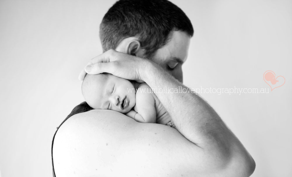 natural light newborn photographer sunshine coast sleeping baby laying on dads arm, with dads hand on babies head