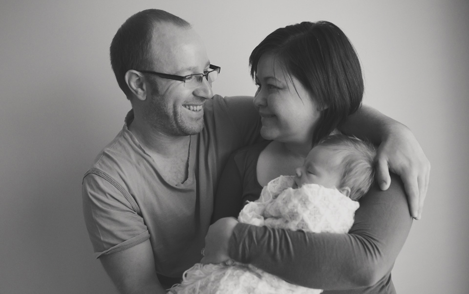 dad smiling looking at mum holding newborn baby