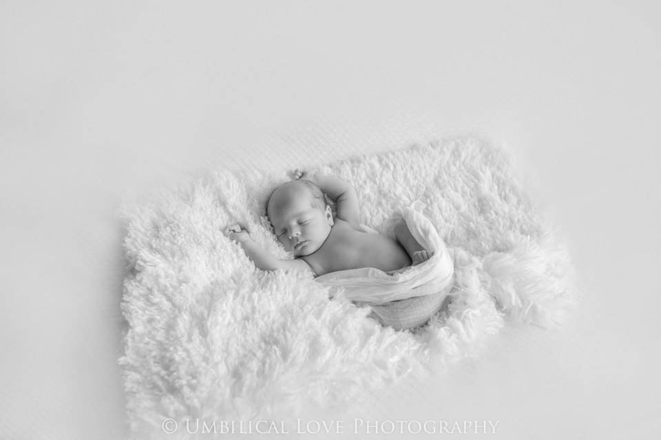 4 week old baby snuggled up curly laying on a fluffy rug all wrapped up