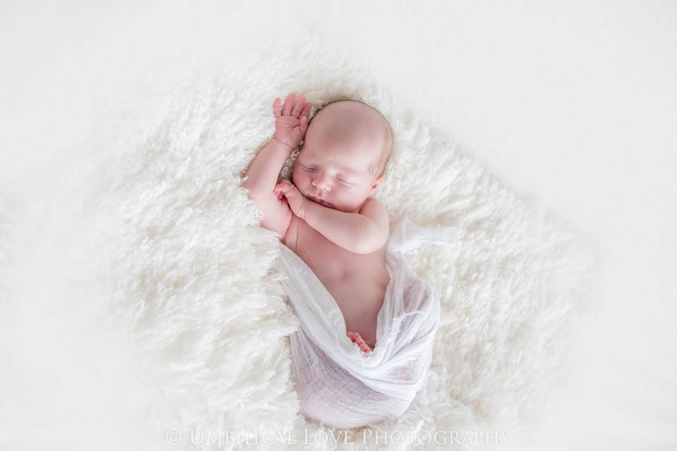 newborn baby with arm up over his head asleep
