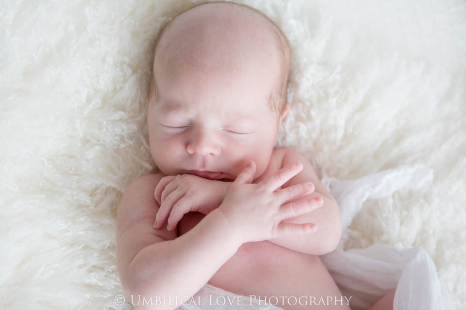newborn baby sleeping with his arms crossed
