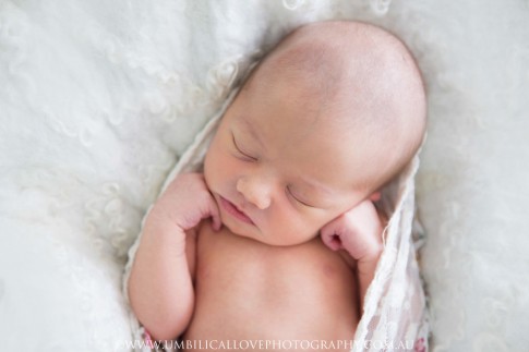 close up of baby sleeping with her hands curled near her face
