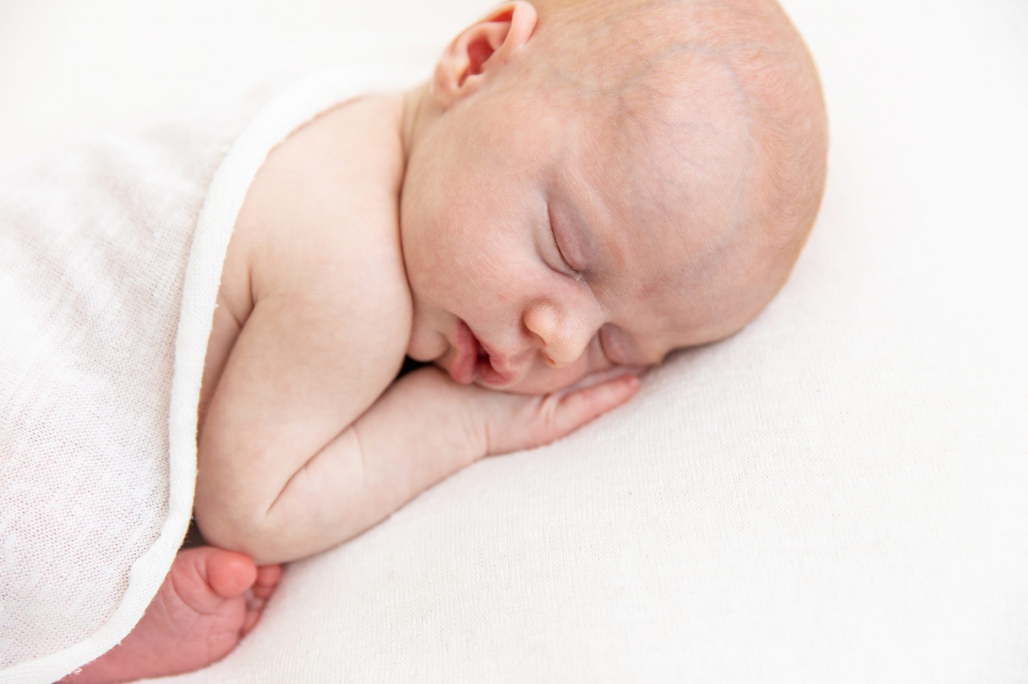Newborn baby girl sleeping with her hand under her cheek