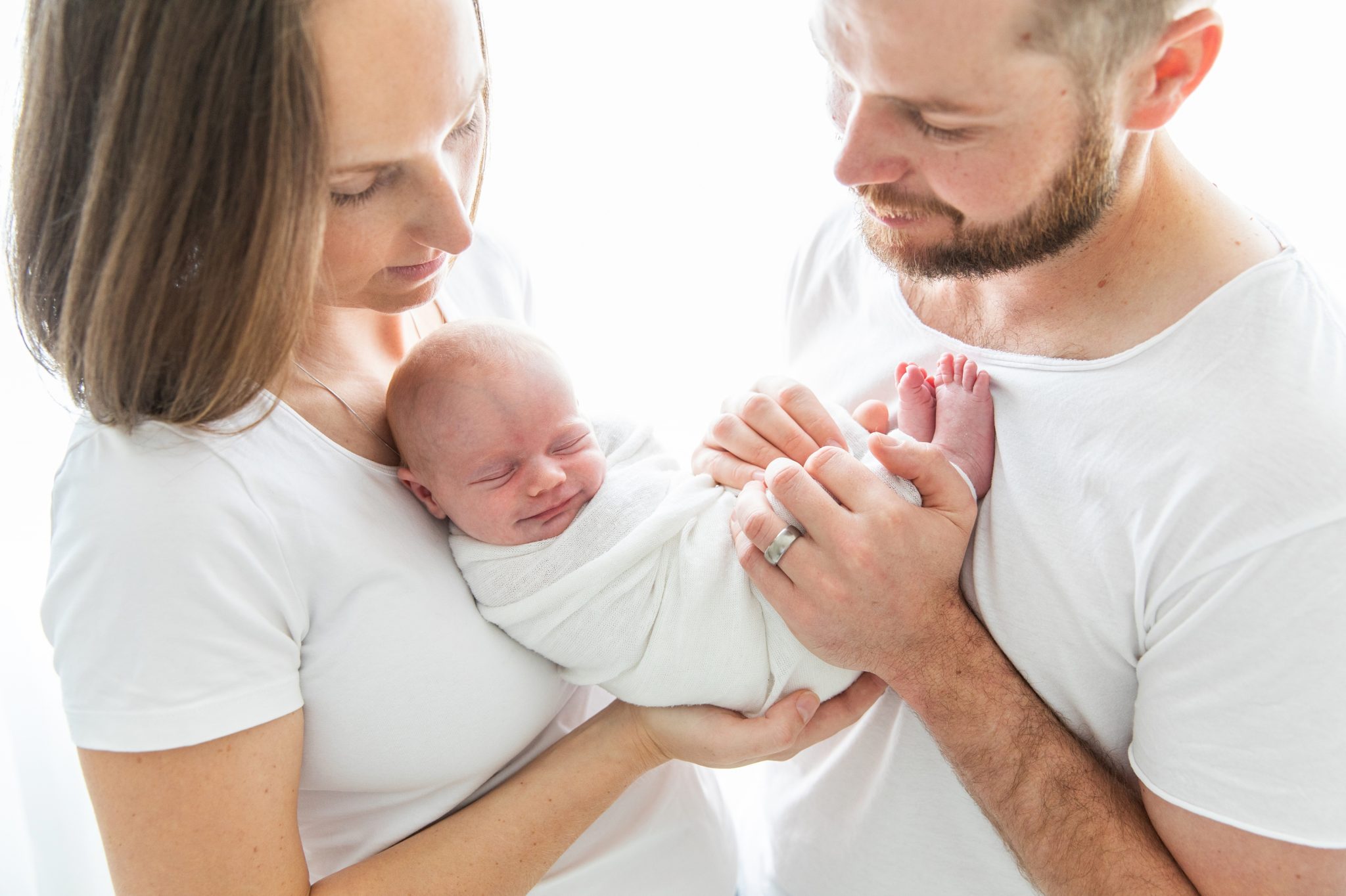 Baby smiles while being held by her parents